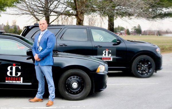 Local private investigator Jeremiah Brooks poses next to two of his company’s vehicles. Photo provided by Alivia Waldron.