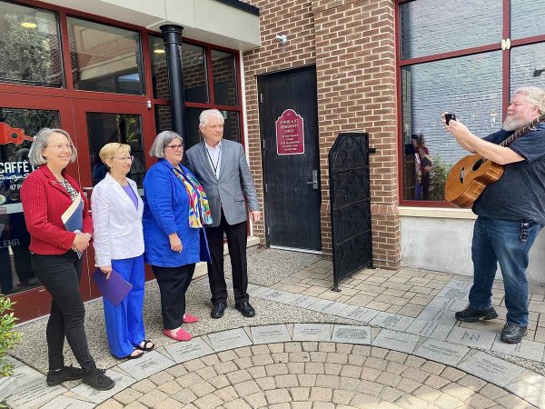 Chicago-based musician Joe Jencks captures an image of Caffe Lena Executive Director Sarah Craig, Director of the state Community Preservation Bureau Kathleen Howe, Assemblywoman Carrie Woerner and Saratoga Springs Mayor John Safford outside Caffe Lena on May 2, 2024. Photo by Thomas Dimopoulos.
