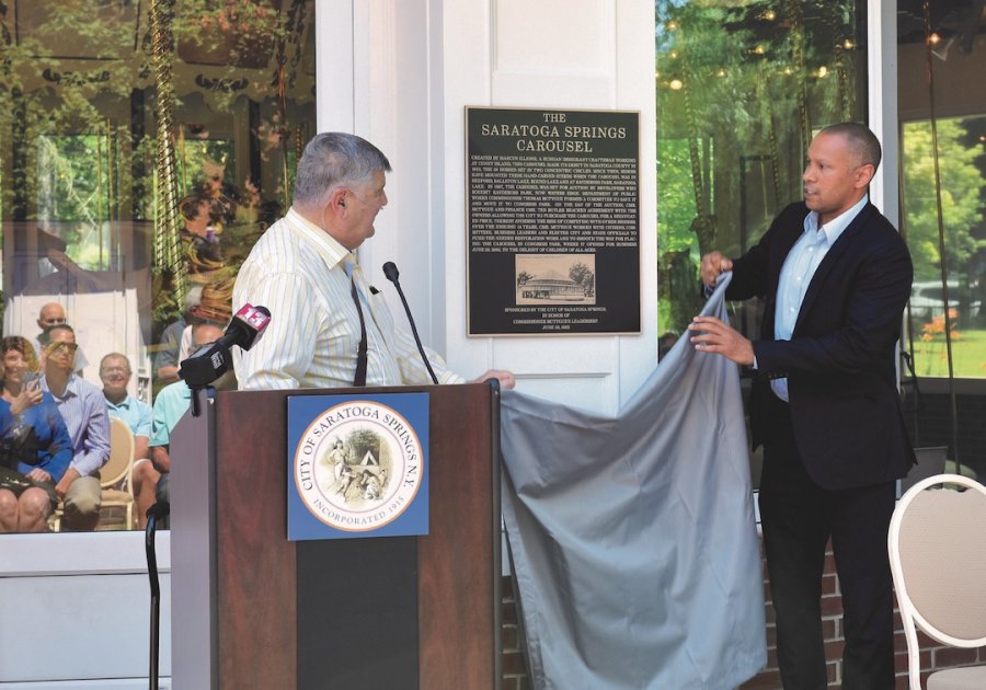 Former Saratoga Springs DPW Commissioner Tom McTygue, at left, and current Commissioner Jason Golub, unveil a plaque in Congress Park on June 29, 2022, detailing the history of the carousel and commemorating the leadership of McTygue. 