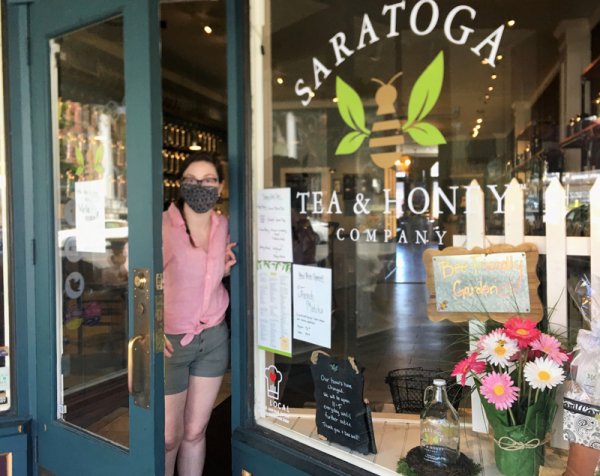 Emma Lance, poking her masked face through the front entry door of the Saratoga Tea &amp; Honey Shop on May 20, 2020. Photo by Thomas Dimopoulos.