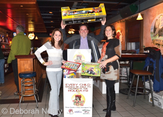 Saratoga Convention and Tourism Bureau President Todd Garofano (center) shows Angela LaTerra and Franklin Community Center’s Jamie Williams the proper way to donate a toy. 